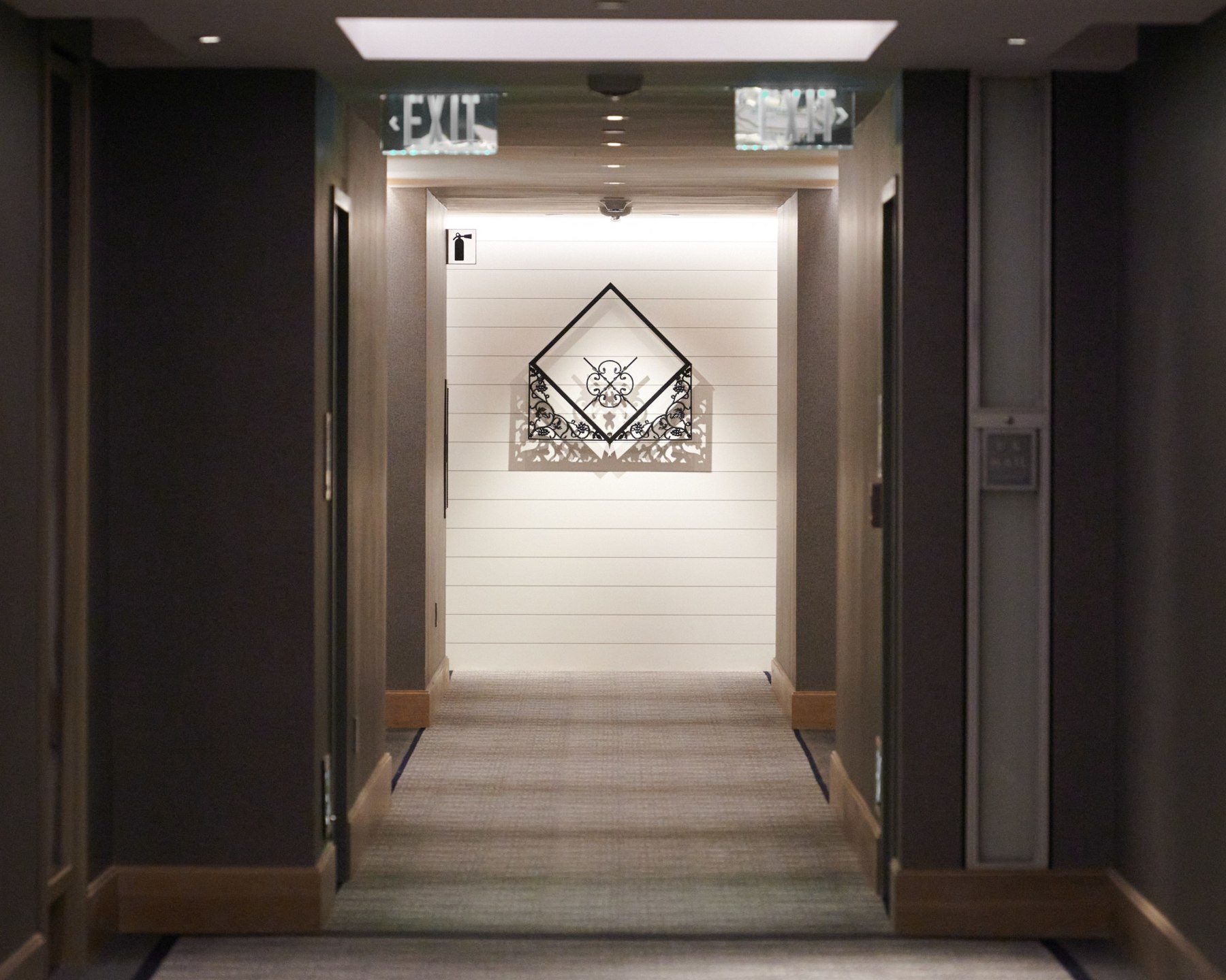 A hotel corridor leading toward the installed geometric ironwork