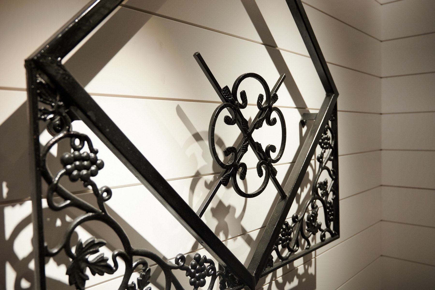 Angled close view of ornamental ironwork and its shadows