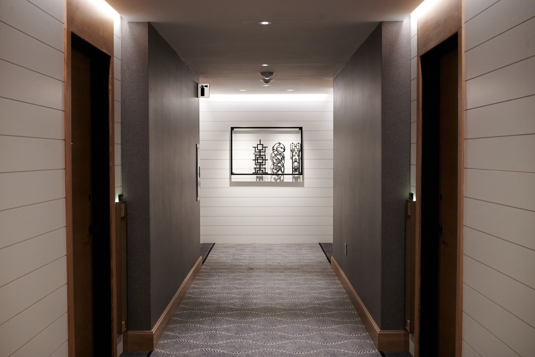 A long hotel corridor with an ironwork sculpture at the far end