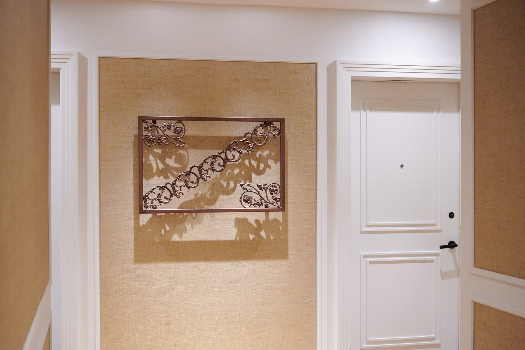 A rectangular ornamental ironwork sculpture installed in a residential corridor