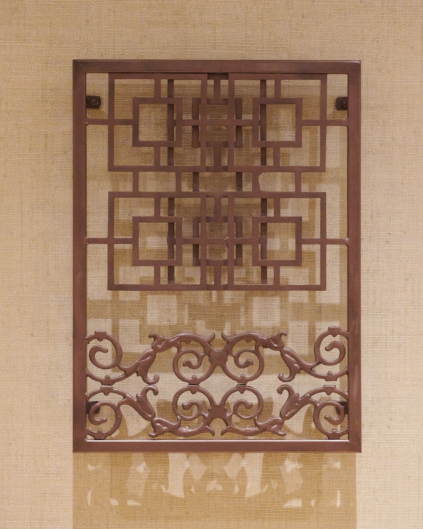 A rectangular iron sculpture combining a geometric grid and ornamental scrolls