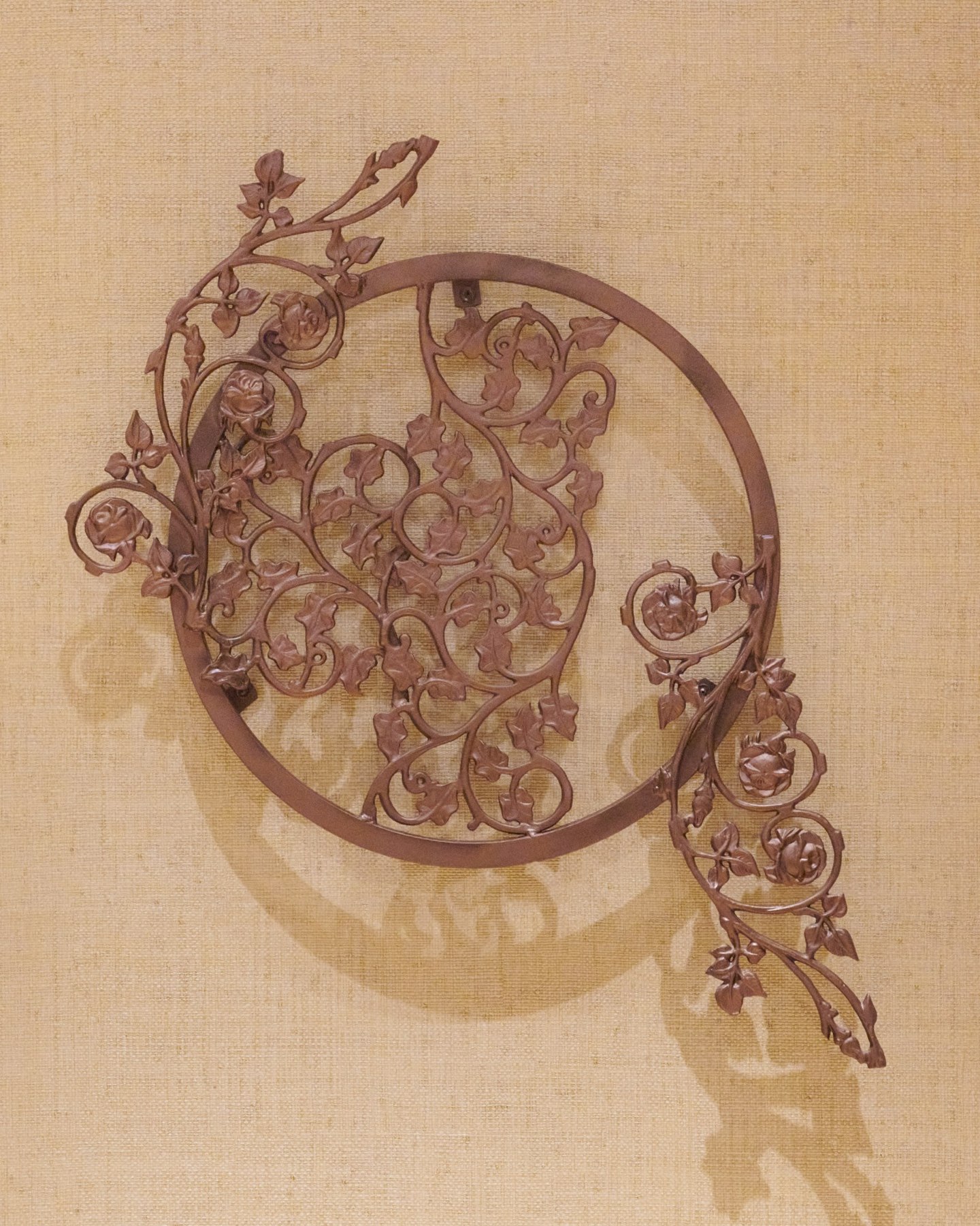 Close view of circular ironwork and its shadows on a textured wall