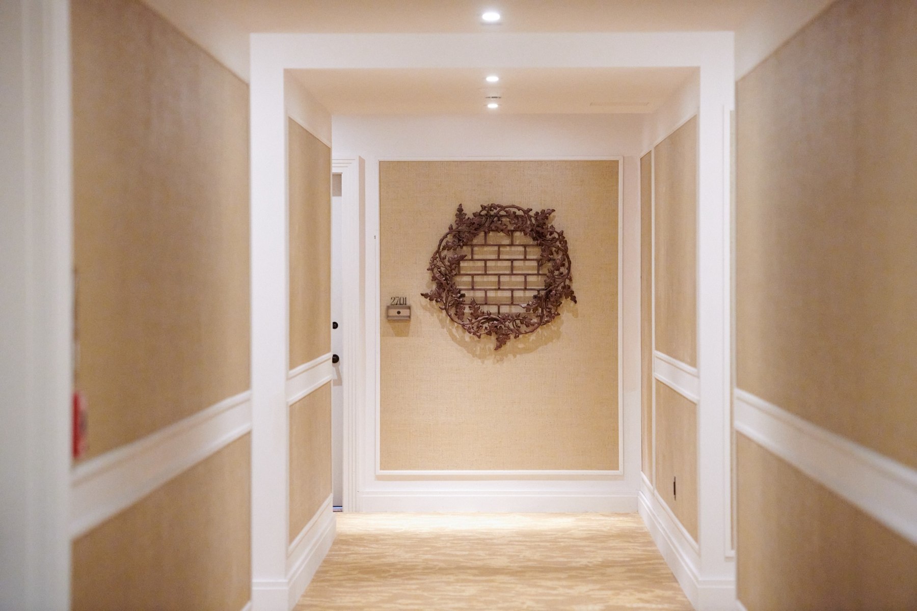 A private residence corridor leading toward a circular ironwork sculpture
