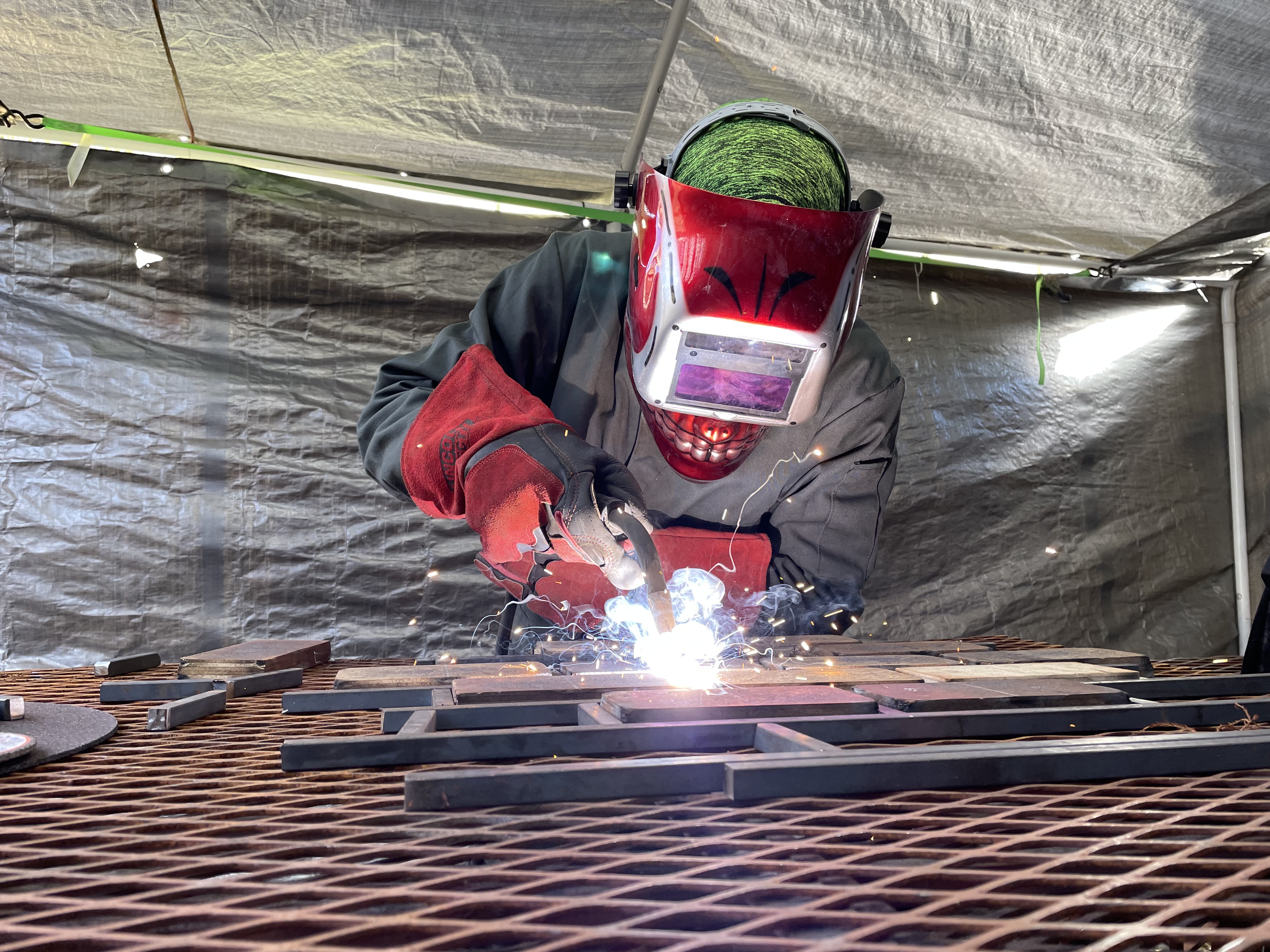 Close view of welding metal components on a workshop table