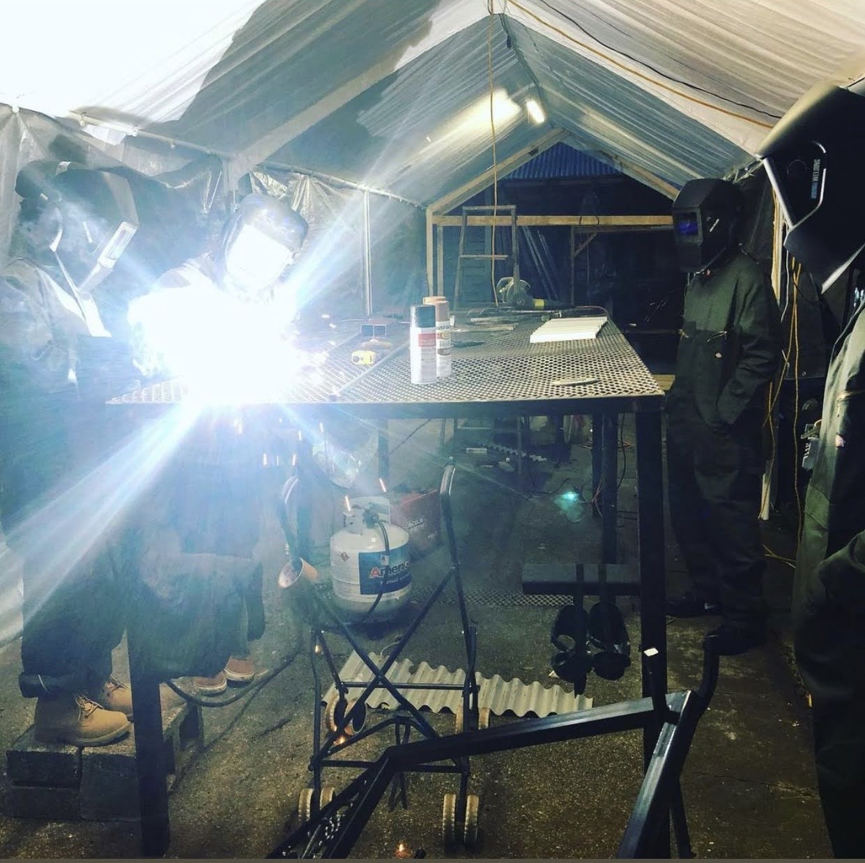 Participants gathered around a welding station in the workshop